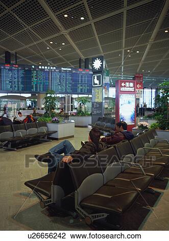 Stock Image - Travelers sitting at airport terminal. Fotosearch