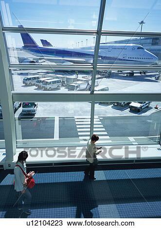 Two travelers walking through airport terminal View Large Photo Image Stock Image - Two travelers walking through airport terminal. Fotosearch