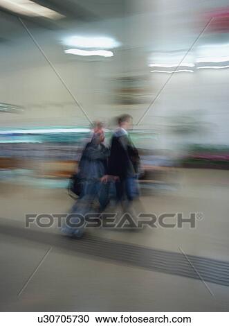 Two travelers walking with luggage at airport, blurred motion View Large Photo Image Stock Image - Two travelers walking with luggage at airport, blurred motion. Fotosearch