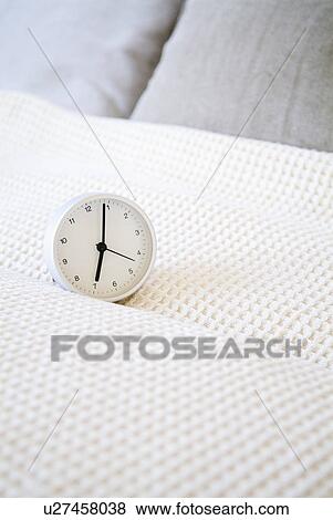 Stock Photo - Alarm clock on bed. Fotosearch