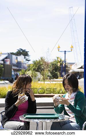 Two young women eating hamburgers View Large Photo Image Stock Image - Two young women eating hamburgers. Fotosearch