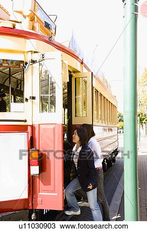 Two young women getting on a tram View Large Photo Image Stock Image - Two young women getting on a tram. Fotosearch