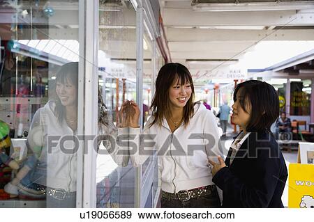 Two young women looking into shop window View Large Photo Image Stock Photo - Two young women looking into shop window. Fotosearch
