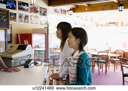 Two young women ordering food at fast food restaurant View Large Photo Image Stock Photo - Two young women ordering food at fast food restaurant. Fotosearch