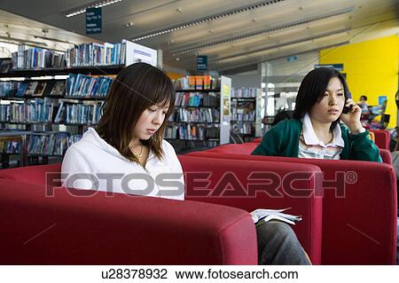 Two young women sitting in library View Large Photo Image Stock Image - Two young women sitting in library. Fotosearch