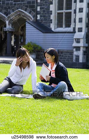Two young women sitting on lawn View Large Photo Image Stock Photo - Two young women sitting on lawn. Fotosearch
