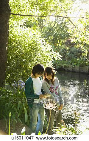 Two young women standing by river View Large Photo Image Stock Photo - Two young women standing by river. Fotosearch