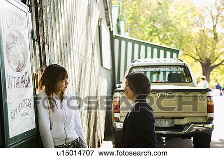 Stock Photo - Two young women talking in front of a truck. Fotosearch