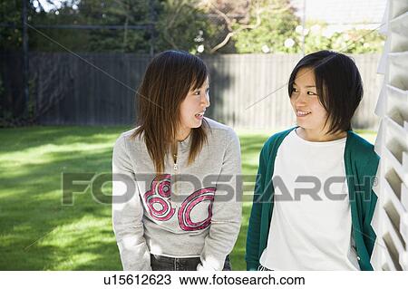 Two young women talking on backyard View Large Photo Image Stock Image - Two young women talking on backyard. Fotosearch