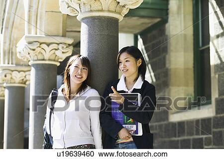 Two young women talking on campus View Large Photo Image Stock Image - Two young women talking on campus. Fotosearch