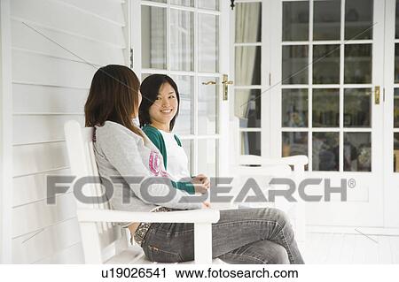 Two young women talking on porch View Large Photo Image Stock Image - Two young women talking on porch. Fotosearch