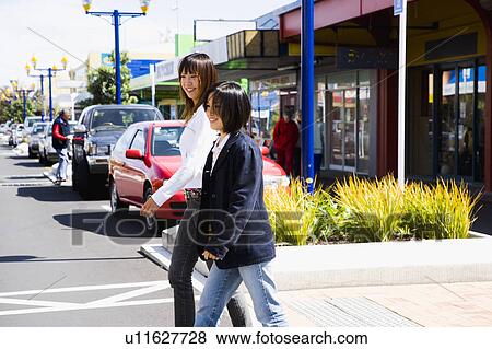 Two young women walking in a town View Large Photo Image Stock Photo - Two young women walking in a town. Fotosearch