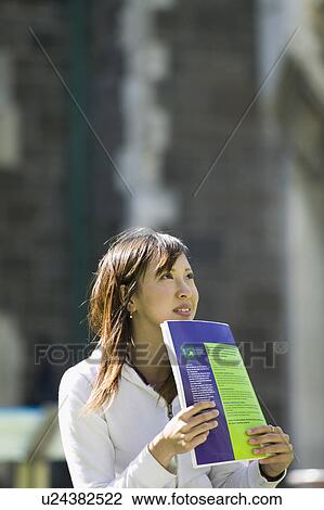 Young woman looking away with textbook View Large Photo Image Stock Image - Young woman looking away with textbook. Fotosearch