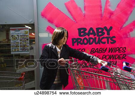 Picture - Young woman moving shopping cart. Fotosearch