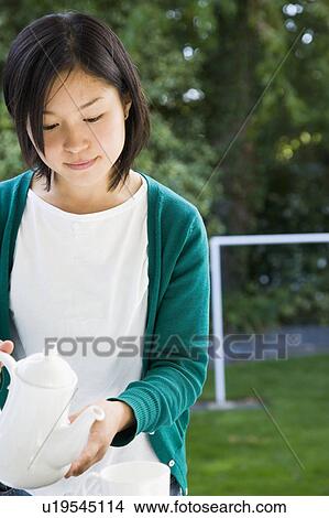 Young woman pouring tea View Large Photo Image Picture - Young woman pouring tea. Fotosearch
