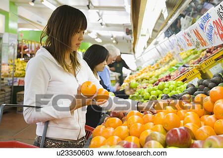 Stock Image - Young woman shopping in supermarket. Fotosearch
