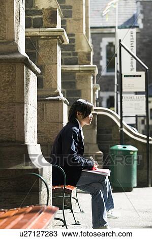Young woman sitting on bench View Large Photo Image Stock Image - Young woman sitting on bench. Fotosearch