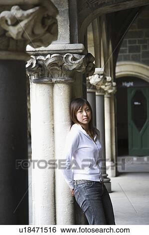 Stock Photograph - Young woman standing against column. Fotosearch