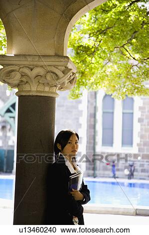 Young woman standing with textbook View Large Photo Image Stock Image - Young woman standing with textbook. Fotosearch