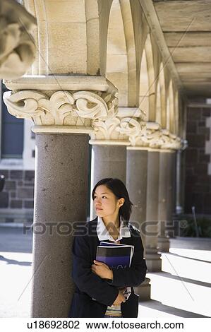 Young woman standing with textbook View Large Photo Image Stock Image - Young woman standing with textbook. Fotosearch