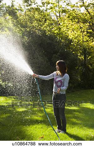 Stock Photo - Young woman watering lawn. Fotosearch