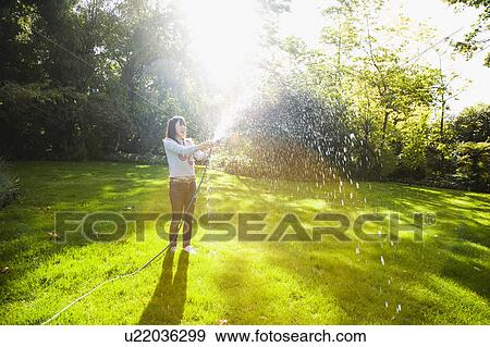 Young woman watering lawn View Large Photo Image Stock Photo - Young woman watering lawn. Fotosearch