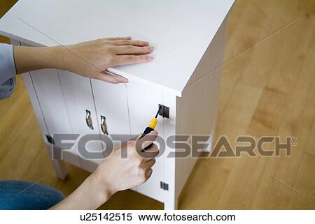 Stock Photography - A woman assembling dresser. Fotosearch