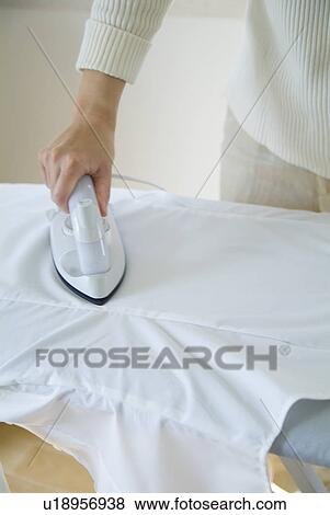 Stock Photo - A woman ironing shirt. Fotosearch