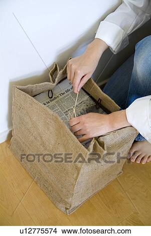 Picture - A woman tying a stack of newspapers. Fotosearch