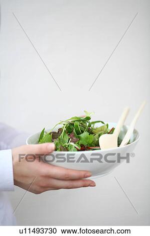 Stock Image - A young woman carrying a bowl of salad. Fotosearch