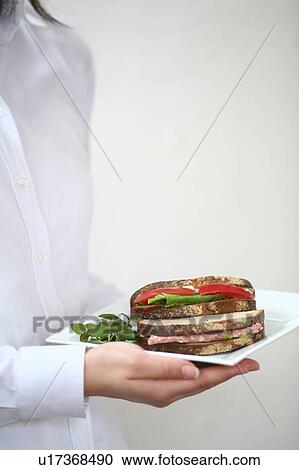 Stock Image - A young woman carrying sandwiches on plate. Fotosearch