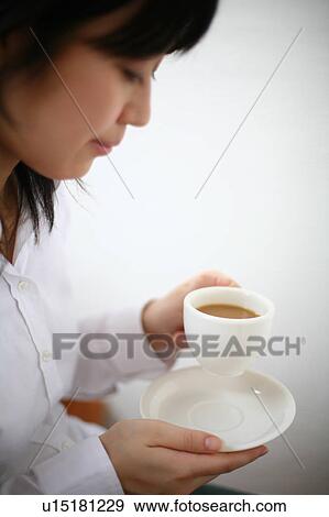 A young woman drinking a cup of coffee View Large Photo Image Stock Photo - A young woman drinking a cup of coffee. Fotosearch
