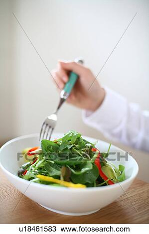 A young woman eating a bowl of salad View Large Photo Image Stock Image - A young woman eating a bowl of salad. Fotosearch