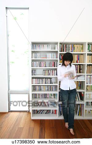 Stock Image - A young woman reading magazine, blurred motion. Fotosearch