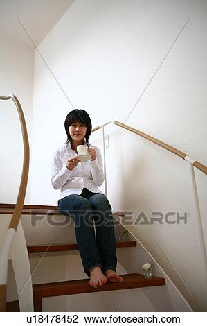 A young woman sitting on staircase View Large Photo Image Stock Image - A young woman sitting on staircase. Fotosearch