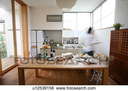 Stock Photo - A young woman walking in kitchen, blurred motion. Fotosearch