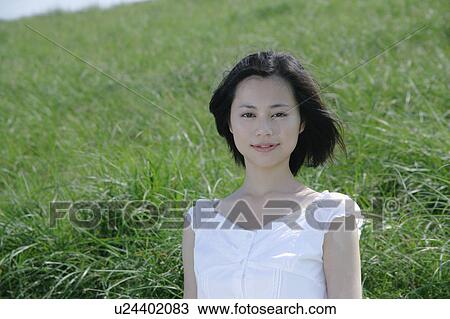 A young woman in grass field View Large Photo Image Stock Image - A young woman in grass field. Fotosearch