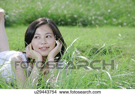 A young woman lying on grass field View Large Photo Image Picture - A young woman lying on grass field. Fotosearch