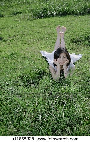 A young woman lying on grass field View Large Photo Image Stock Photo - A young woman lying on grass field. Fotosearch