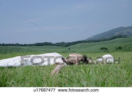 Stock Photo - A young woman lying on grass field. Fotosearch