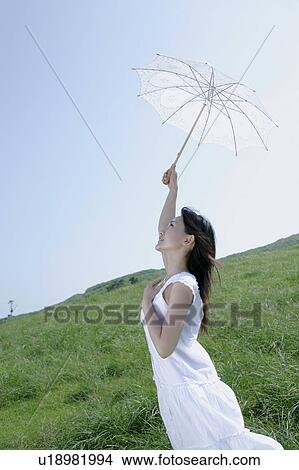 A young woman raising hand with parasol View Large Photo Image Picture - A young woman raising hand with parasol. Fotosearch