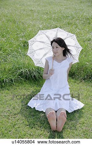 A young woman sitting on grass field View Large Photo Image Picture - A young woman sitting on grass field. Fotosearch