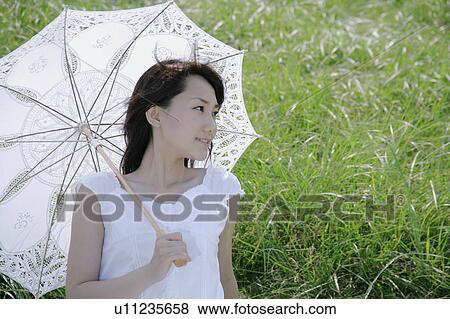 A young woman sitting on grass field View Large Photo Image Stock Photo - A young woman sitting on grass field. Fotosearch