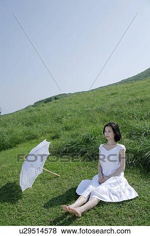 A young woman sitting on grass field View Large Photo Image Stock Photo - A young woman sitting on grass field. Fotosearch