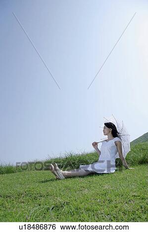 A young woman sitting on grass field View Large Photo Image Stock Photograph - A young woman sitting on grass field. Fotosearch
