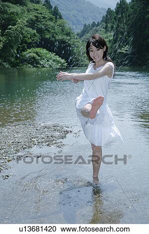 Stock Image - A young woman splashing water. Fotosearch