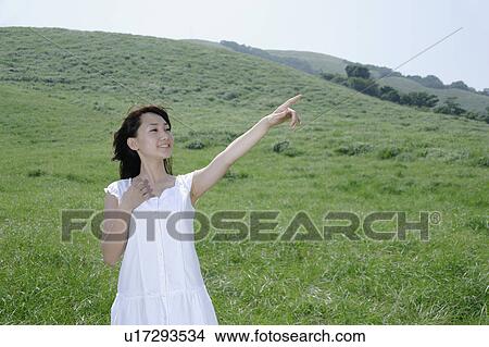 A young woman standing in field View Large Photo Image Picture - A young woman standing in field. Fotosearch