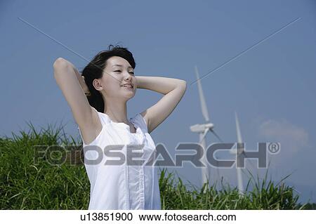 Stock Image - A young woman standing in field. Fotosearch