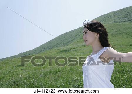 Stock Image - A young woman standing in field. Fotosearch