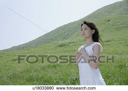 A young woman standing in field View Large Photo Image Stock Image - A young woman standing in field. Fotosearch